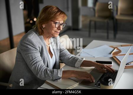 Pleased female company director typing on laptop keyboard Stock Photo