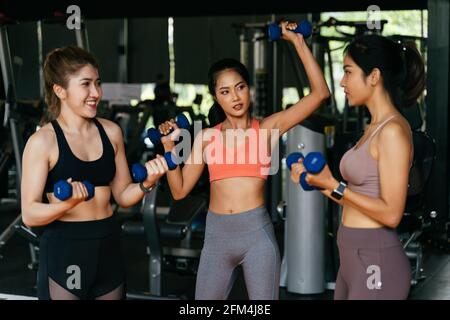 Happy young multiracial team of female athletes in sportswear training together with dumbbells in fitness club Stock Photo