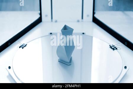 Bright blue object printed by 3d printer on 3d printer inside. Stock Photo