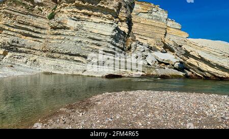 Low angle shot of a cliff with layers and a small river Stock Photo