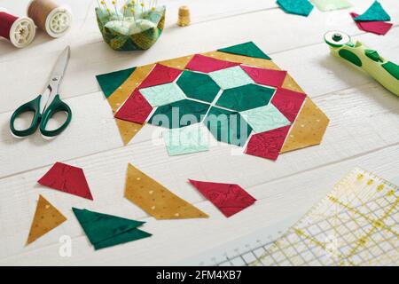 Pieces of fabric laid out in the shape of a patchwork block, sewing and quilting accessories. Stock Photo