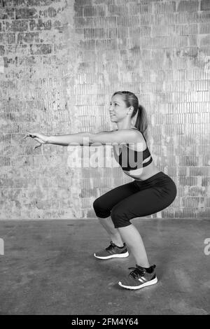 Concentrated european woman doing squats and workout indoors Stock Photo