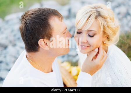Man touches his hand to the cheek of closed-eyed woman while sitting on a blanket Stock Photo