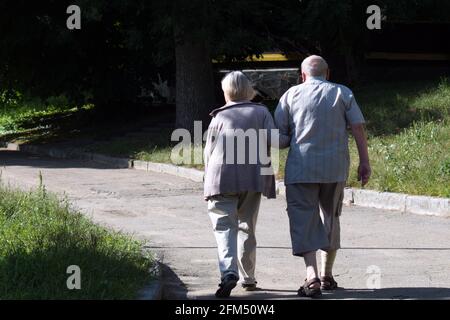 elderly man and woman walking down the path in park Stock Photo