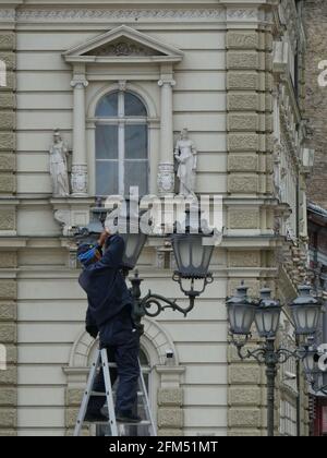 NOVI SAD, SERBIA - May 29, 2019: Novi Sad, Serbia, May 29th 2019. - Male electrician repairing street lamp  in front of townhall in Novi Sad, Serbia Stock Photo