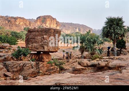 Strange rock formation in front of the Falaise de Bandiagara. In between Dogon women carrying baskets on their heads.  08.11.2003 - Christoiph Keller Stock Photo