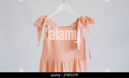 Muslin Eco Friendly Clothing, Organic Cotton Muslin Clothes. Natural tones dresses hanging on a hanger on white background Stock Photo