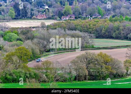 An elevated view of a tractor ploughing a field on a spring day at Westcott near Dorking in the Surrey Hills England UK Stock Photo