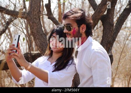 Young man and woman taking a selfie  with colored powder during holi festival Stock Photo