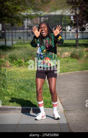 A middle aged woman in athletic clothing waves and smiles at this photographer. In a park in Queens, New York. Stock Photo
