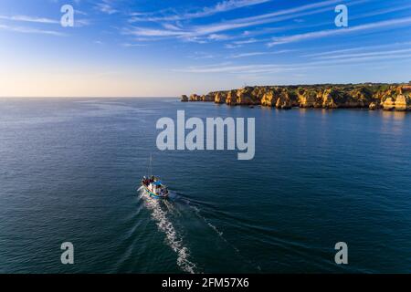 Lagos, Portugal - February 9, 2020: Aerial view of a small fishing boat navigating along the scenic Ponta da Piedade, near the city of Lagos, in Algar Stock Photo