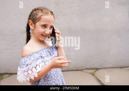 happy child, girl talking on cell, smart phone, outdoors. Positive human emotions, facial expressions, Stock Photo