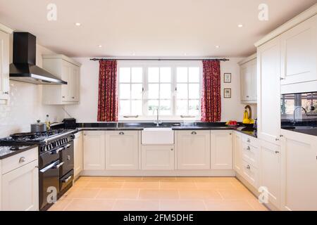 Shaker style farmhouse kitchen with neutral painted wood modular units, UK kitchen interior design Stock Photo