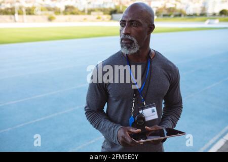 African american senior male coach holding digital tablet standing in the stadium Stock Photo