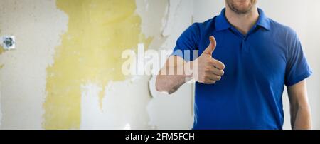 house renovation service - construction worker, handyman with thumb up gesture standing in old room. copy space Stock Photo