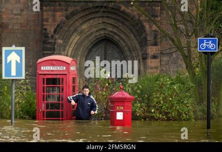 Floods by the Abbey in Shrewsbury November 2000, one of the locals stands between the telephone box and letter box in waist height water Stock Photo