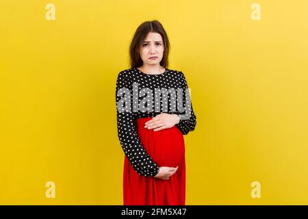 Sad and stressed pregnant woman isolated on colored background. Stock Photo