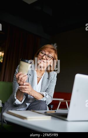 Positive delighted woman looking at paper cup Stock Photo