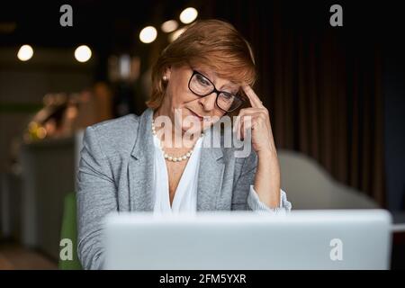 Concentrated mature woman being deep in thoughts Stock Photo