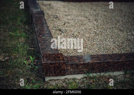 border of grave site made of polished granite. Small pebbles inside. Stock Photo