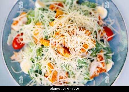 Meal of salad caesar on table. Dish with tomatoes, herbs, chicken and egg sprinkled with cheese. Concept of menu in cafe or restaurant. Stock Photo