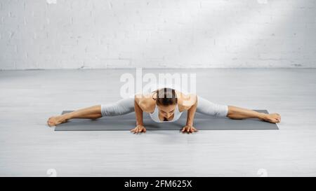 Woman doing handstand and split on yoga mat Stock Photo