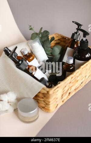 collection of various beauty hygiene tubes, bottles and jars in basket on gray background Stock Photo