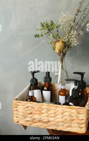 collection of various beauty hygiene tubes, bottles and jars in basket on gray background Stock Photo