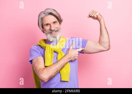 Photo of mature man happy smile point finger hands muscles sportive strong ad tied sweater isolated over pink color background Stock Photo