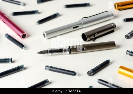 Ink pens and ink cartridges are scattered on the table. Stock Photo