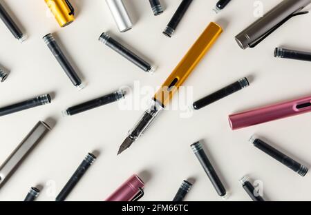 Ink pens and ink cartridges are scattered on the table. Stock Photo