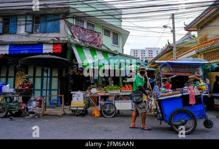 A male food vendor pushes his blue cart along the road in Chinatown, Bangkok, Thailand. Stock Photo