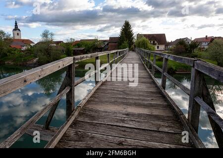 wooden bridge over the river Krka in Slovenia, with the sourounding small town Kostanjevica Stock Photo