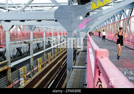 A woman jogging on the walking path of Williamsburg Bridge with subway tracks beside.New York City.USA Stock Photo