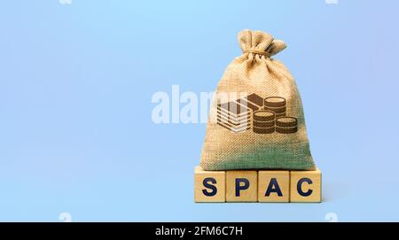 Wooden blocks with the word SPAC and money bag - Special purpose acquisition company. Simplified listing of company, merger bypassing stock exchange I Stock Photo
