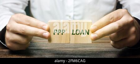 Businessman puts blocks with words PPP loan - Paycheck Protection Program. Loan designed to provide a direct incentive for small businesses to keep th Stock Photo
