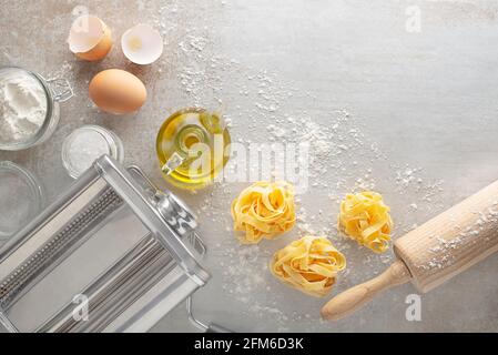 Making homemade fresh pasta with pasta machine on kitchen table with some ingredients around Stock Photo