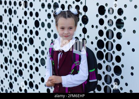 Portrait of pretty schoolgirl wearing stylish uniform with backpack holding colorful notebooks. Back to school concept Stock Photo