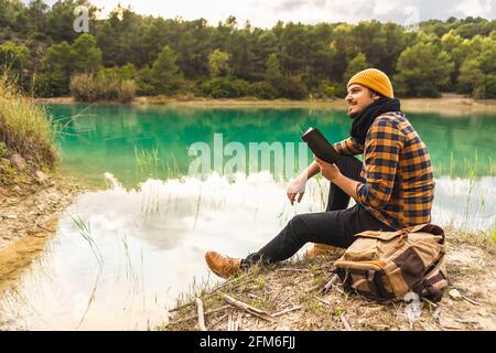 Spanish traveler enjoying reading a book sitting on a peaceful lake Stock Photo