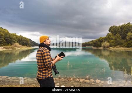 Tourist guide cheking guide book with hat and camera in the lake Stock Photo
