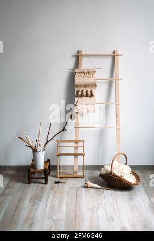 Still life with wool in basket, art instruments, frame, and weaved rug Stock Photo