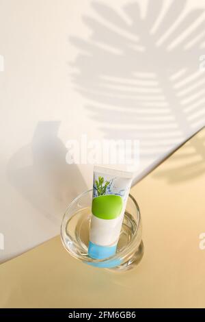Green and white plastic cosmetics paste cream or gel tube, isolated on white background with leaf Stock Photo
