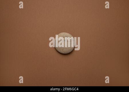 Rounded gray striped stone on brown background , trend minimal style Stock Photo