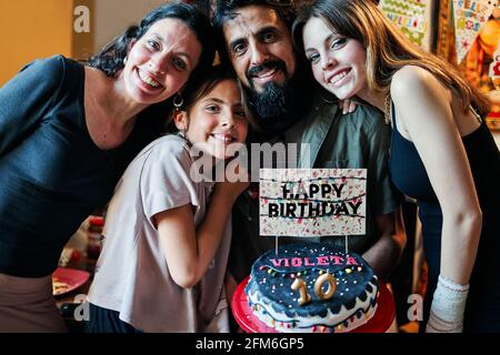 Portrait of a Latino family celebrating little girl's 10th birthday Stock Photo