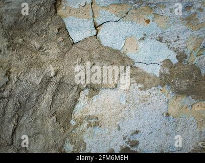 Weathered and cracked concrete wall maintained through time with blue lime and different mortar mixes. Peeling plaster from cement structure surface. Stock Photo