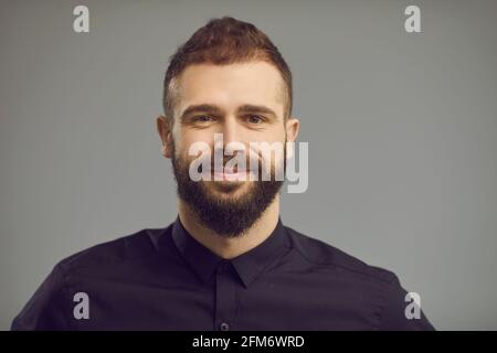 Handsome bearded man with smile on face headshot portrait over gray backgound Stock Photo