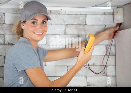 female electrician using multimeter on circuit breaker cabinet Stock Photo
