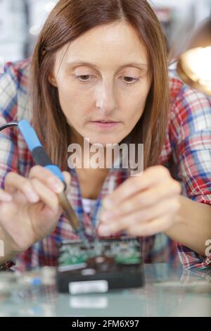 woman soldering elements of circuit board Stock Photo