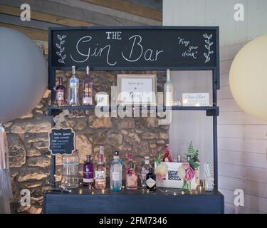 A gin bar with many colourful bottles of gin in front of a stone wall at a party, event or wedding Stock Photo