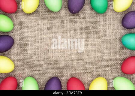 Multicolored Easter eggs on a burlap background. Easter frame. Stock Photo